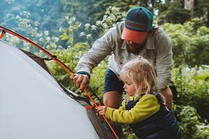 Child helps father to set camping tent travel family vacations hiking outdoor a