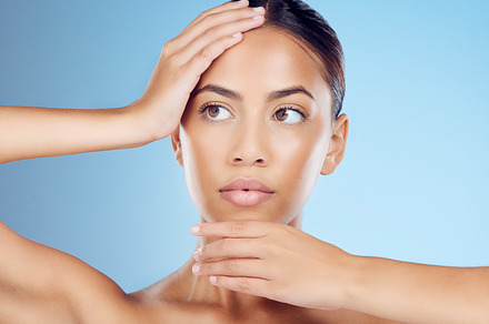 Face, hands and woman skincare on blue background for beauty, wellness and cosmetics from salon spa. Makeup, facial and studio model with dermatology of healthy aesthetic, laser results or clean glow, a Photo by Peopleimages.com