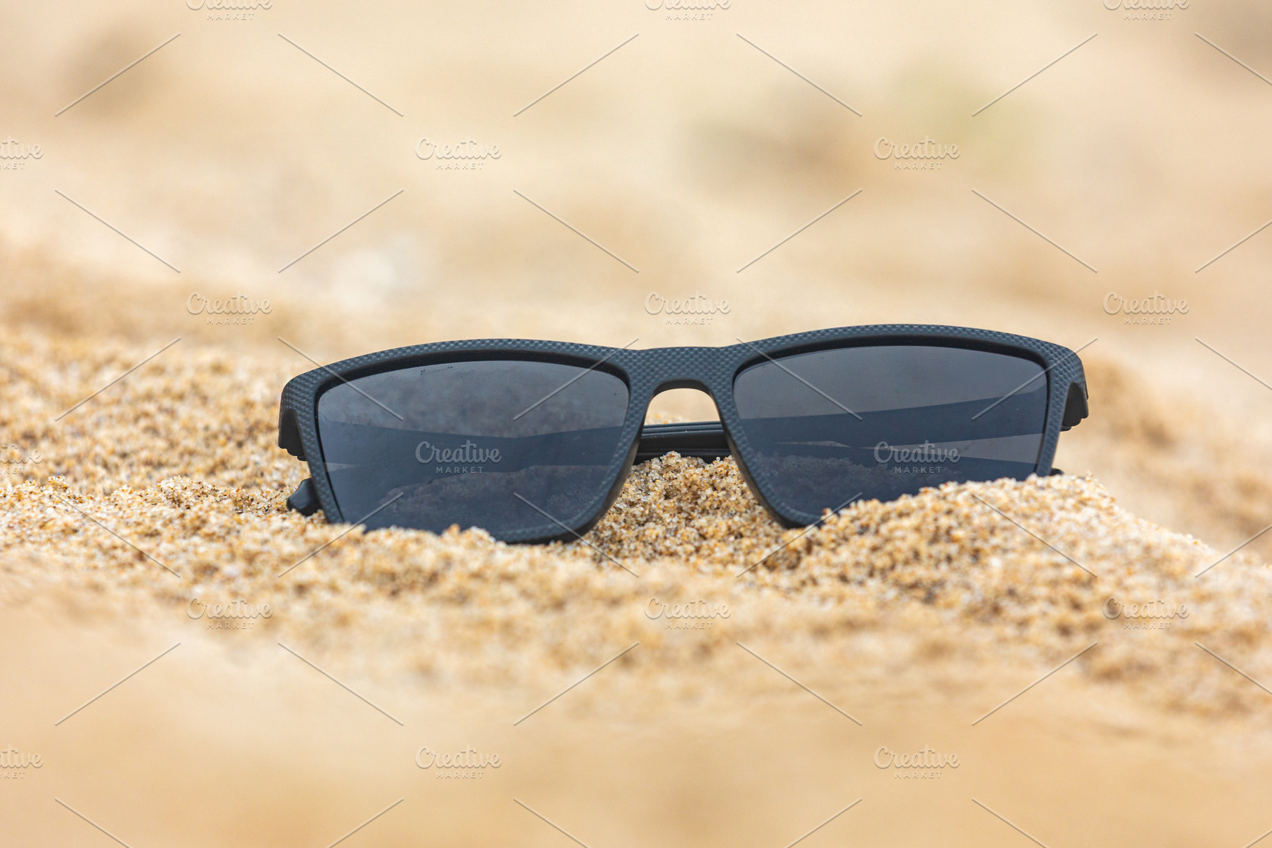 Close-up of black sunglasses partially buried in soft beach sand, capturing a r, a Holiday Photo by Ales Munt