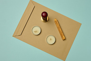 Craft envelope, wax seal, candles, and sealing wax stick on a tu, a Business Photo by ndanko