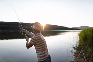 Man fishing by a lake during sunset., a Sports & Recreation Photo by HalfPoint
