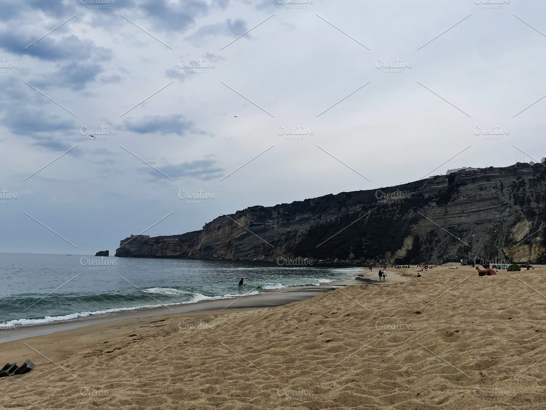 Peaceful coastal view of Nazare Beach under cloudy skies in Portugal, a Photo by AS photostudio