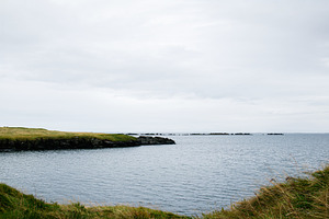 Peaceful coastal landscape of Iceland with ocean and grassy cliffs under cloudy, a Nature Photo by AS photostudio