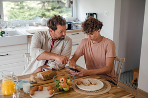 Father guiding teenage son using, a Technology Photo by HalfPoint