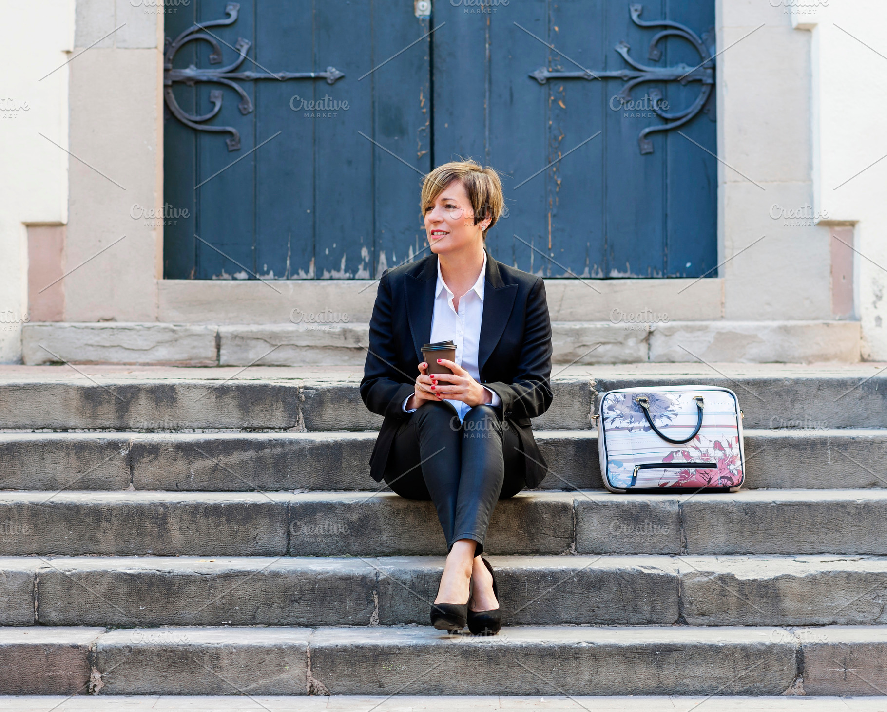 Businesswoman sitting on steps with coffee cup, a Photo by RF Images
