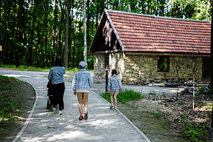 Family walking on a path near a rustic house in the forest, a Person Photo by AS photostudio