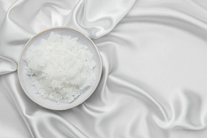 Magnesium flakes in a bowl resting on elegant white silk fabric, a Health & Medical Photo by Olena Rudo