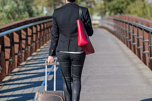 Businesswoman walking with suitcase on city bridge, a Photo by RF Images