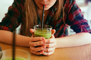 Girl drinking a green smoothie stock