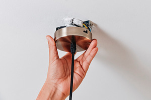 a man positions a ceiling light canopy on the ceiling, a Photo by Nito