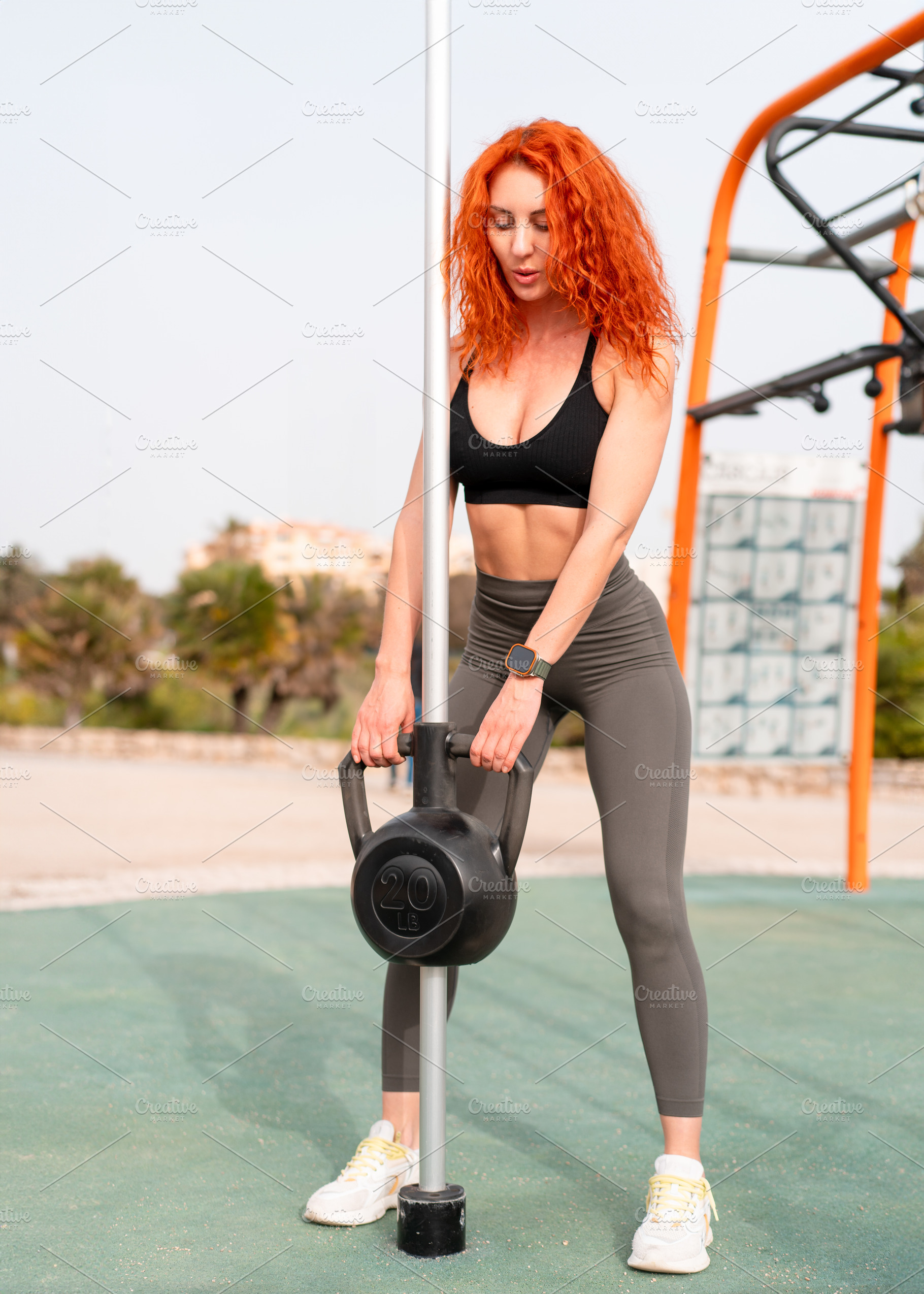 Determined sporty woman pulling kettlebell on pole at outdoor gym, a Person Photo by andreonegin market