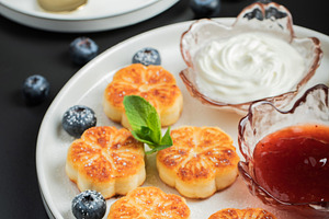 Cottage cheese pancakes, syrniki, curd fritters decorated with strawberry and r, a Food & Drink Photo by Budarinphoto