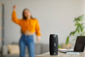 Young lady dancing to popular music at home, selective focus on portable wirele, a Photo by Prostock-Studio