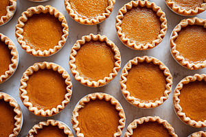 Mini pumpkin pie cups arranged neatly on a baking tray with golden crusts and s, a Food & Drink Photo by AlyaAnd