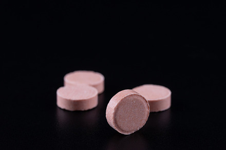 Pink tablet with two pills in backgr, a Health & Medical Photo by AlexBush