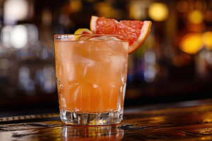 Red grapefruit cocktail in glass on wooden table, a Food & Drink Photo by AlyaAnd