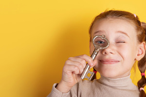 Smiling girl holds an antique key to her eye against a bright ye, a Person Photo by Ales Munt
