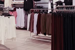 Rows of clothing on hangers in a retail store, showing different styles and col, a Photo by Studio ANNA