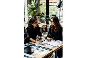 Two Asian businesswomen discussing a, a Person Photo by Sergey Kotenev