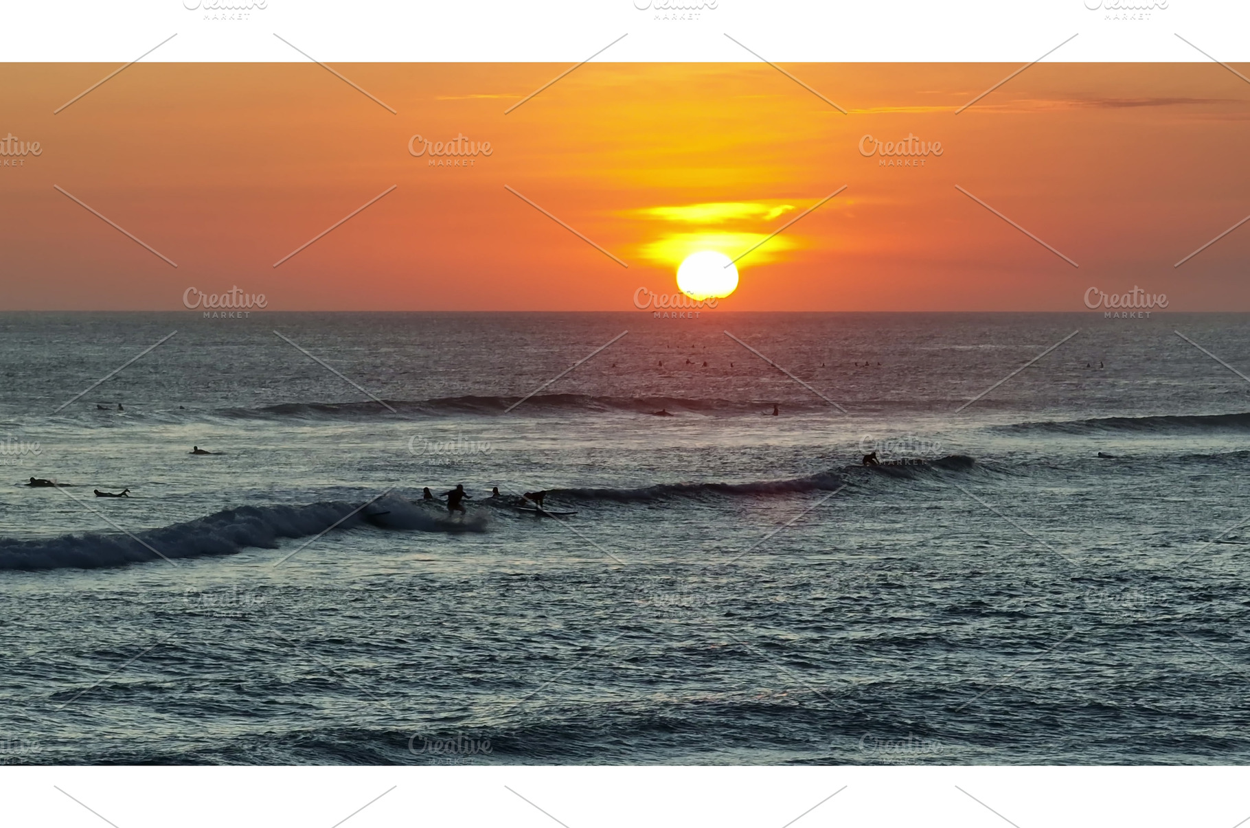 Surfers riding waves during sunset, a Sports & Recreation Photo by Goinyk