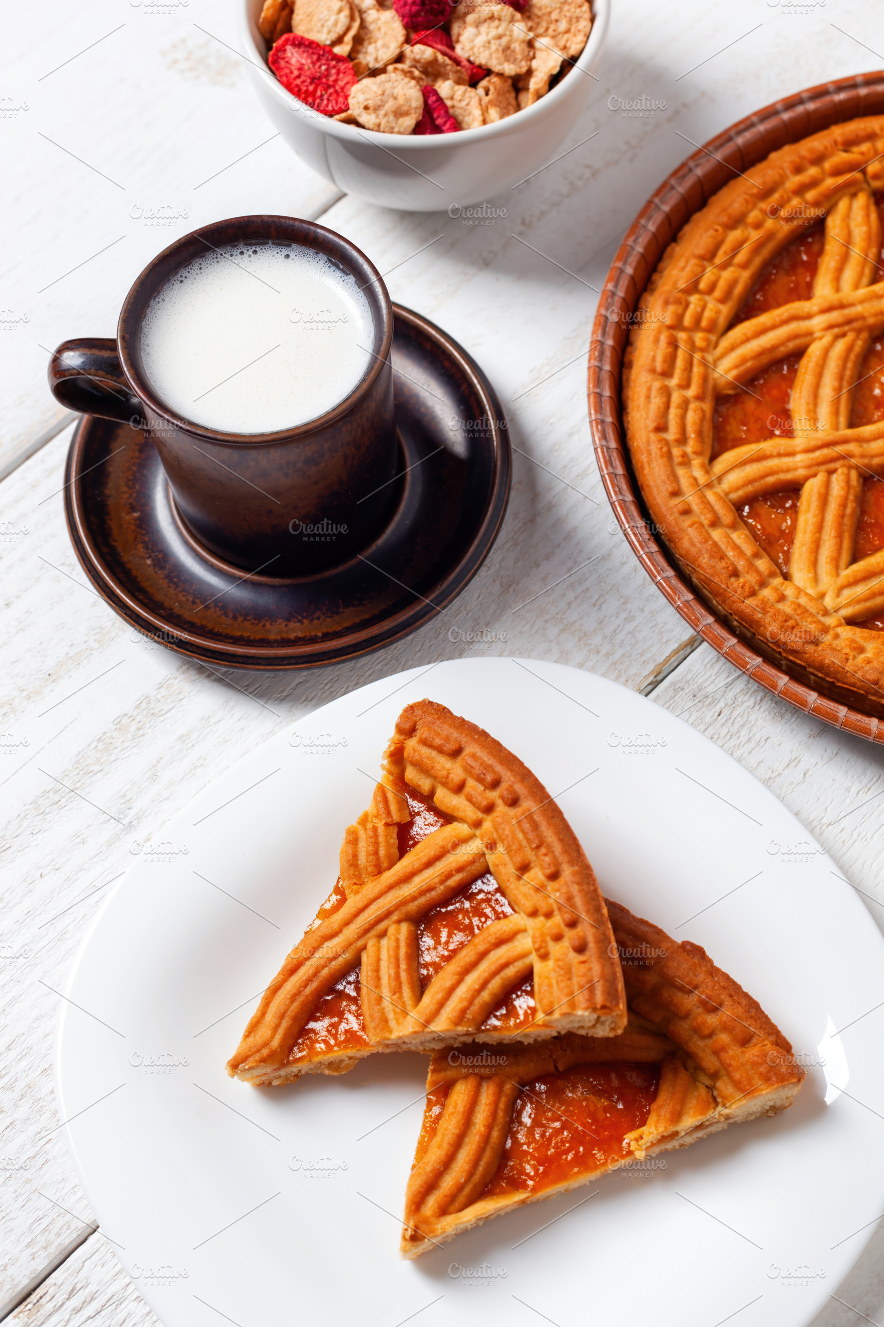 Delicious breakfast with jam tart, milk and cereals on white wooden table, a Food & Drink Photo by Antonio Gravante Market