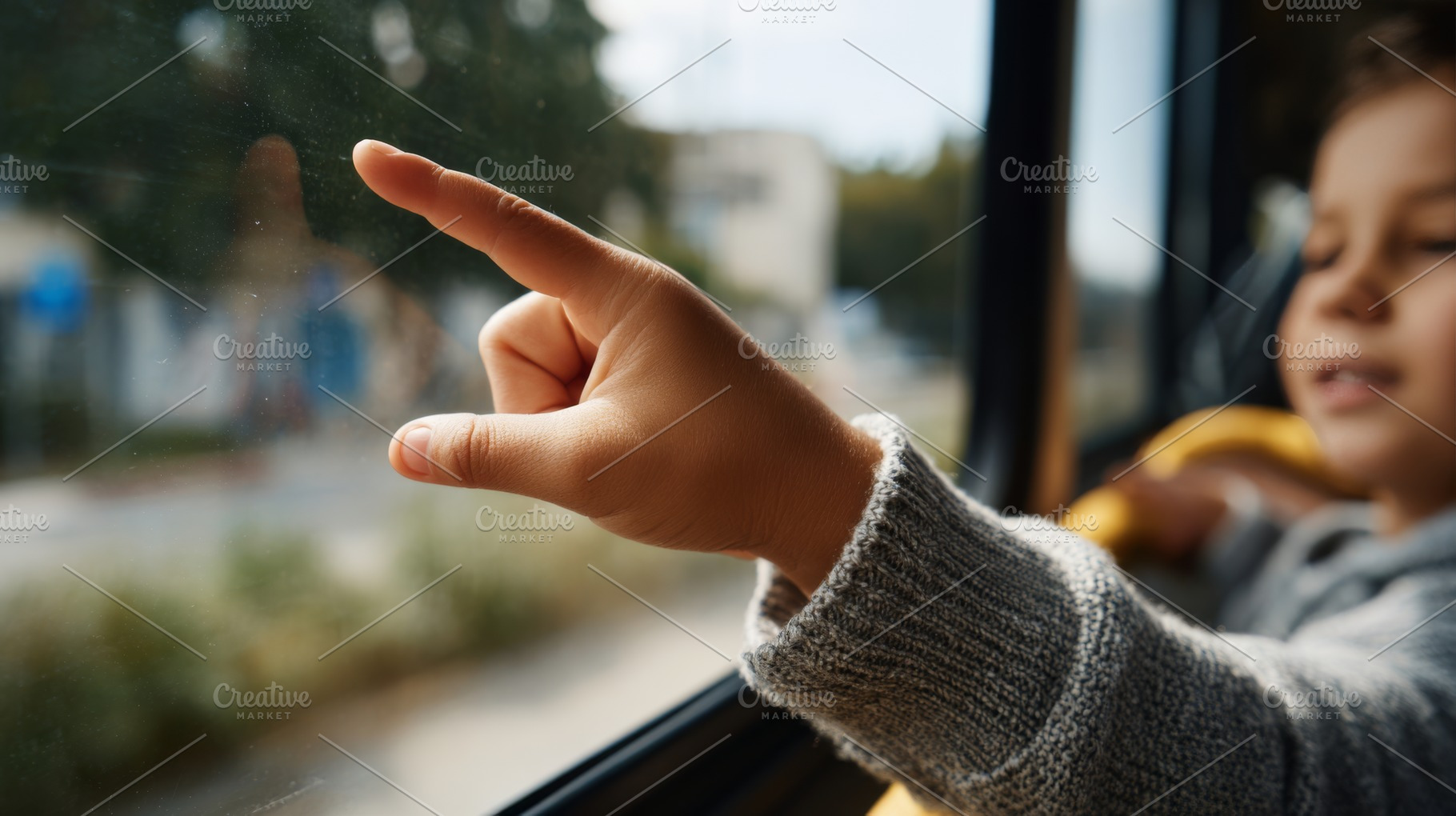 A young child with curly hair excitedly points out the window on a bus ride, ca, a Business Photo by ImageMir