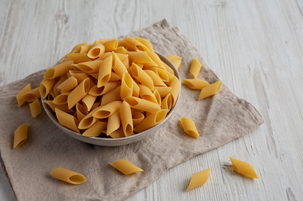Raw Organic Dry Pennoni Pasta in a Bowl, side view., a Food & Drink Photo by LiudmylaChuhunova