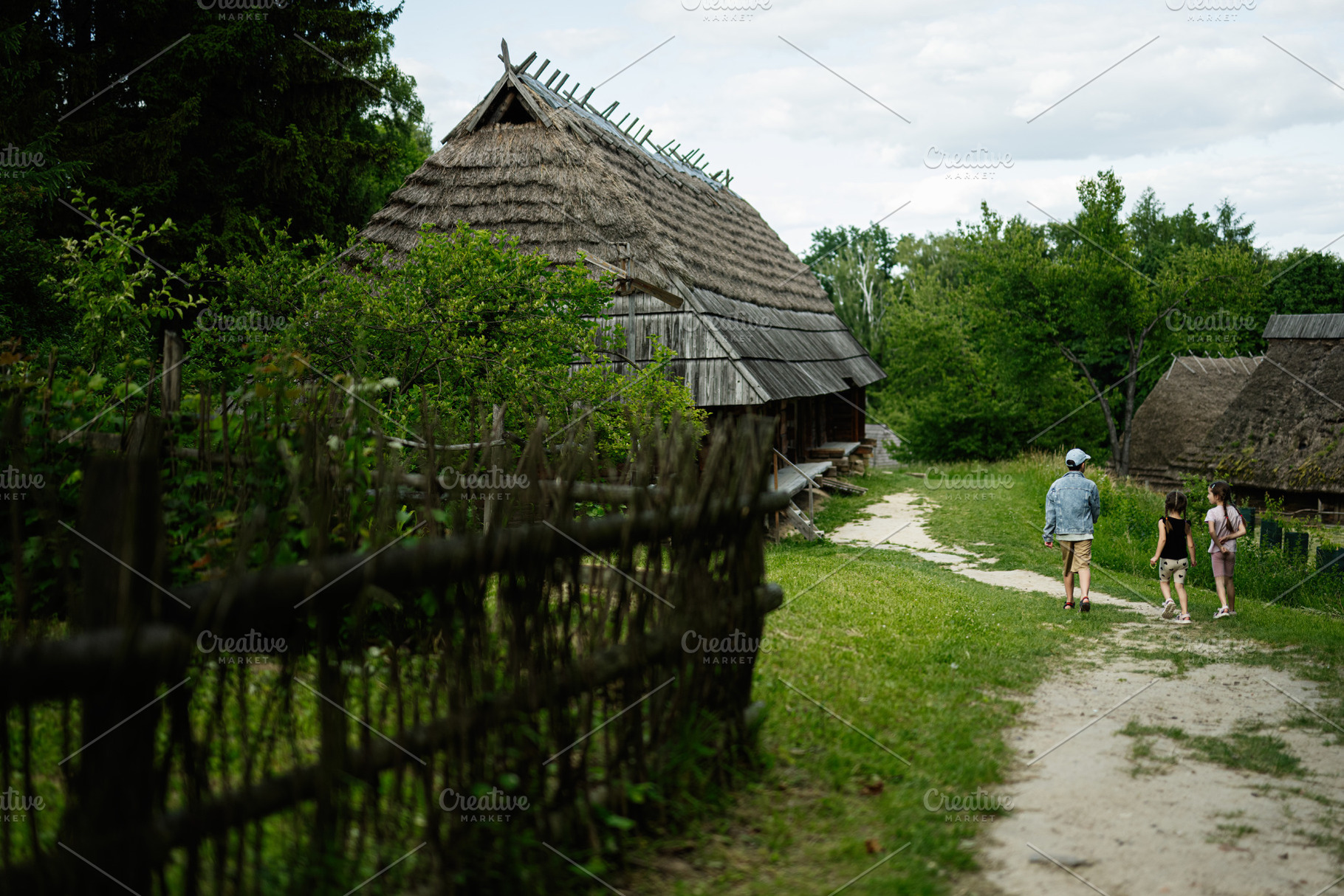 Kids strolling through a rustic village garden with traditional wooden cottages, a Person Photo by AS photostudio