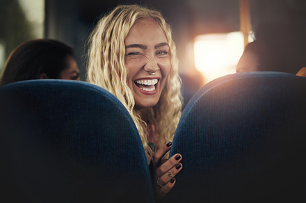 Young woman laughing and winking while sitting on a bus containing adults, a Person Photo by Stefan & Janni