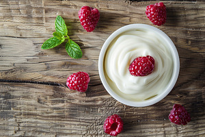 Bowl with fresh raspberries and yogurt on wooden table, a Food & Drink Photo by AlyaAnd