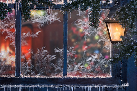 Beautiful Christmas window. Snow, lights a lantern, icicles. Through the window you can see the room with the fireplace and the Christmas tree