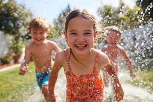 Children joyfully running through sprinklers on a sunny day in the backyard, a Person Photo by AlyaAnd