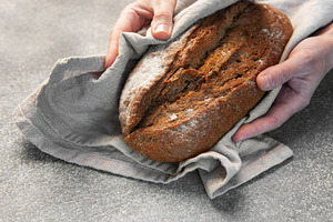 Hands holding freshly baked artisan rye bread, a Food & Drink Photo by Olena Rudo