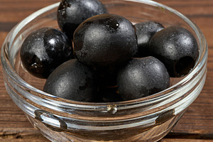 Pitted olives in a glass bowl on a wooden table, a Food & Drink Photo by ndanko