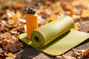 Yoga mat and water bottle amidst golden autumn leaves in the park during a peac, a Photo by AlyaAnd