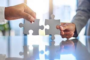 Two professional hand connecting two puzzle pieces on a desk, a Business Photo by DanFLCreativo