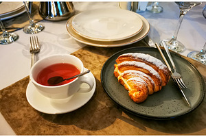Croissant with custard, cup of tea, a Food & Drink Photo by sceptical cactus