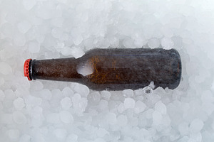 Brown beer bottle buried in a pile of ice cubes, a Food & Drink Photo by Davizro's Market