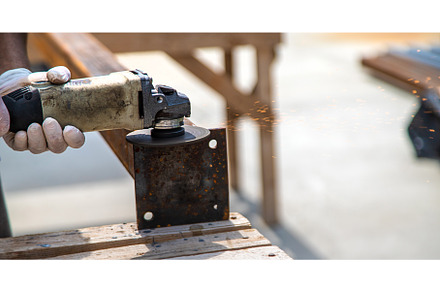 A man processes a metal pole, an Industrial Photo by yanadjana