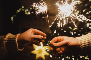 Happy New Year! Burning sparklers in hands on background of chri, a Holiday Photo by Sonjachni