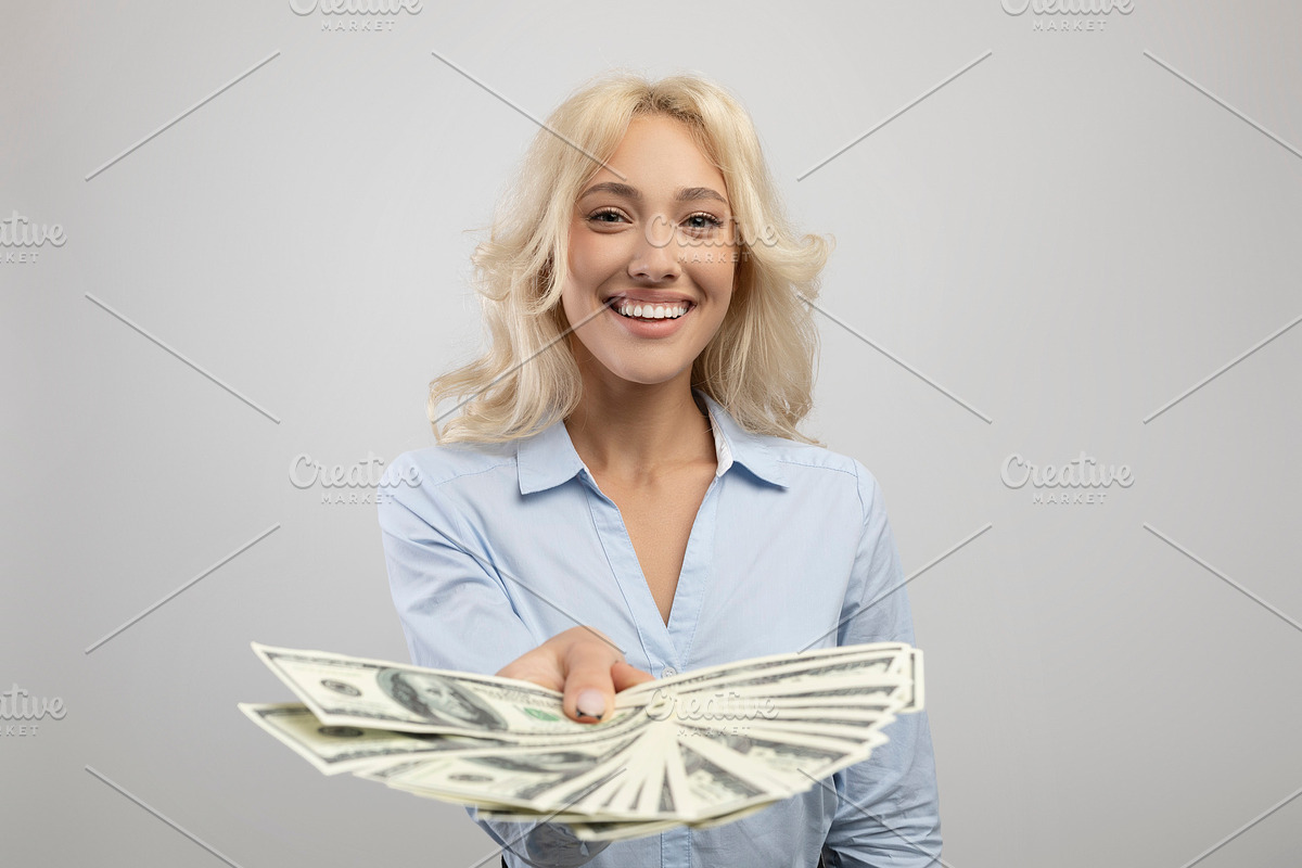 Happy young business lady holding fan of American money, showing banknotes to c, a Photo by Prostock-Studio (Photo 1 of 2)