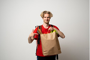 Young delivery man in a red uniform, a Person Photo by volodymyrshtun13795