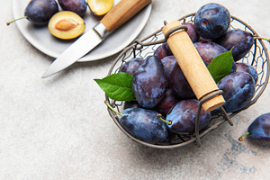 Fresh plums in basket with sliced fruit, a Food & Drink Photo by Olena Rudo