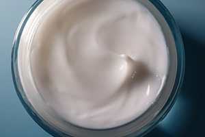 Skincare cream smoothing texture in glass jar on blue background for beauty and, a Photo by Studio ANNA