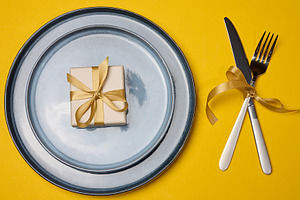 A festive table setting on a yellow background with a gray plate, a Food & Drink Photo by ndanko