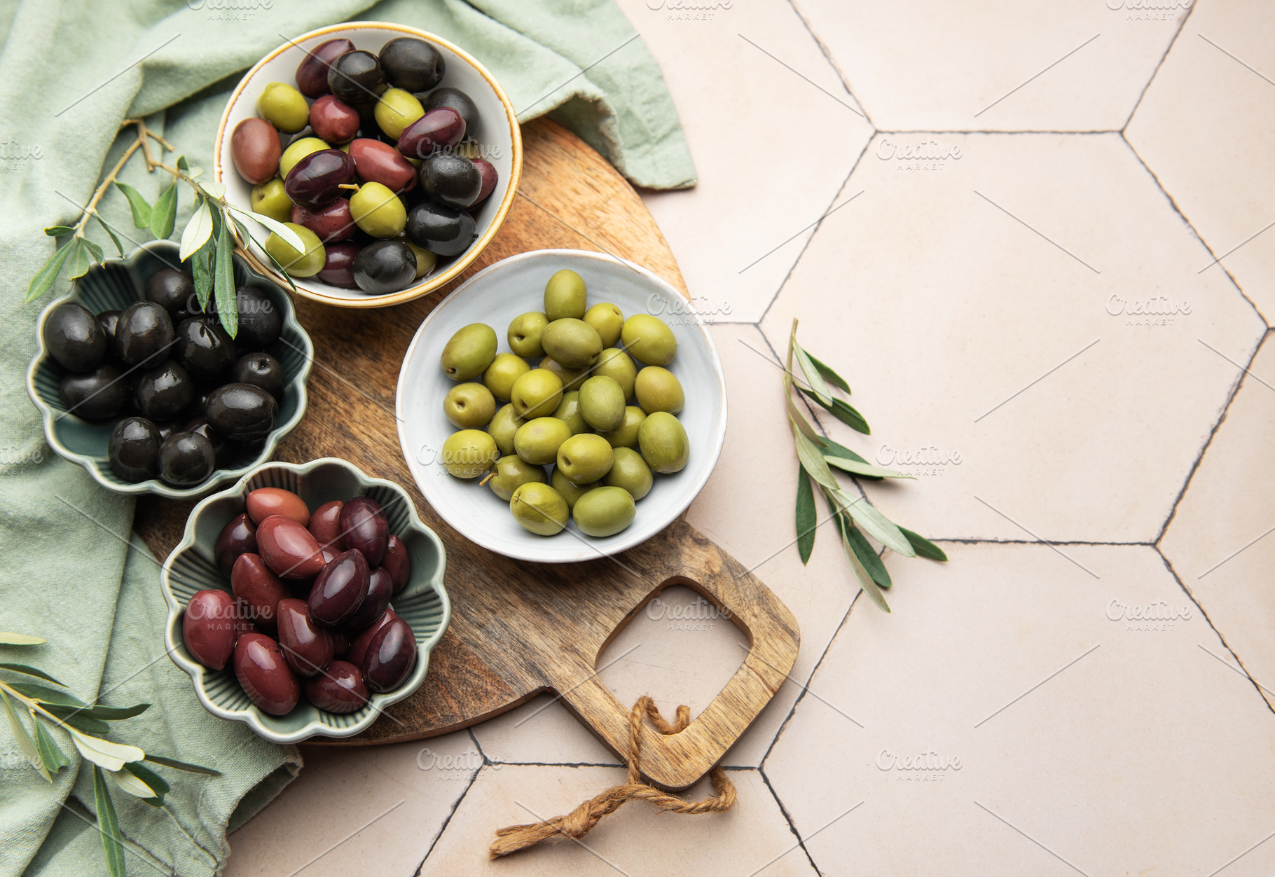 Green, black and kalamata olives in bowls on wooden board, a Food & Drink Photo by Olena Rudo