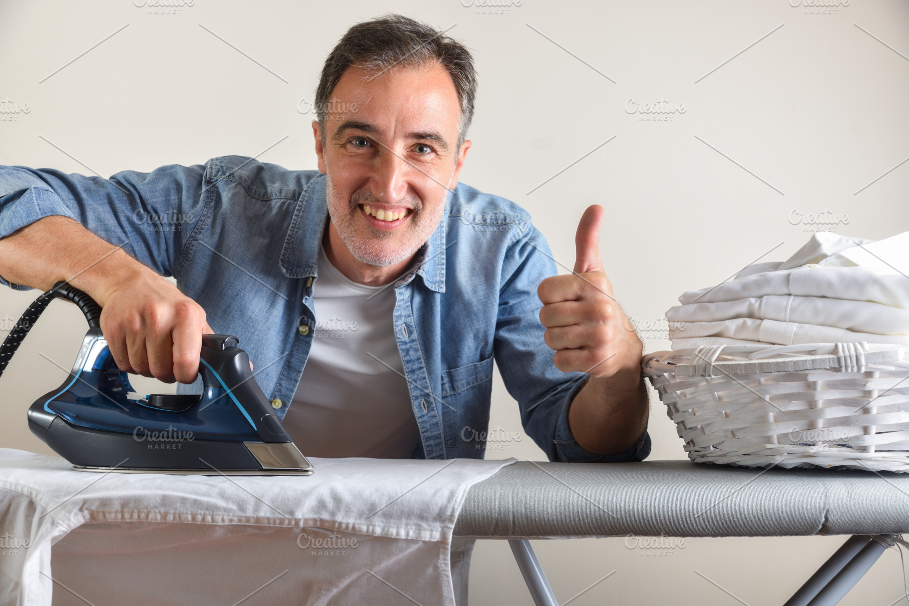 Man ironing shirt on an ironing board with ok gesture, a Sports & Recreation Photo by Davizro's Market