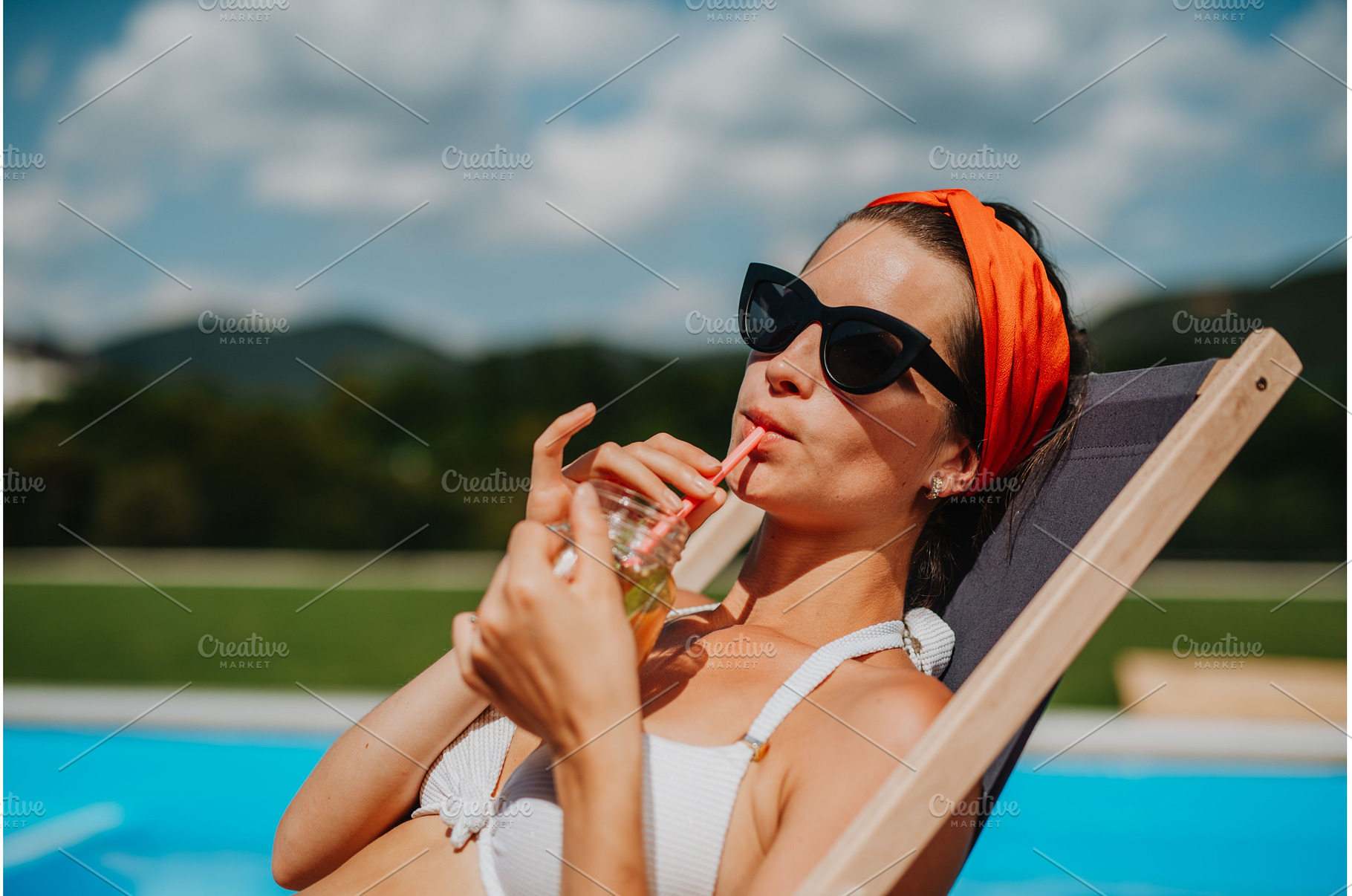 Young woman sitting by swimming pool, a Person Photo by HalfPoint