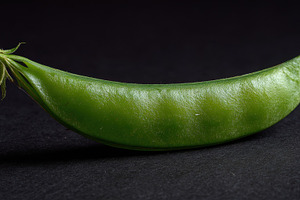 Green pea pod on dark surface, a Photo by Beautiful things
