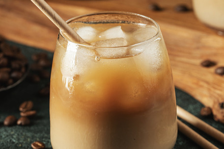 Ice coffee in a tall glass with cream poured over, ice cubes and, a Food & Drink Photo by Budarinphoto